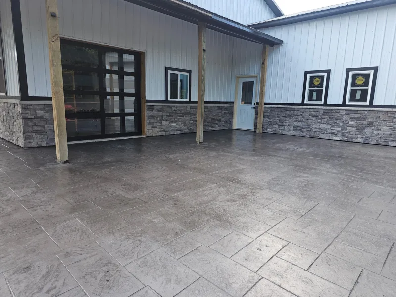 Covered porch with black glass garage door, stone wainscot and stamped concrete