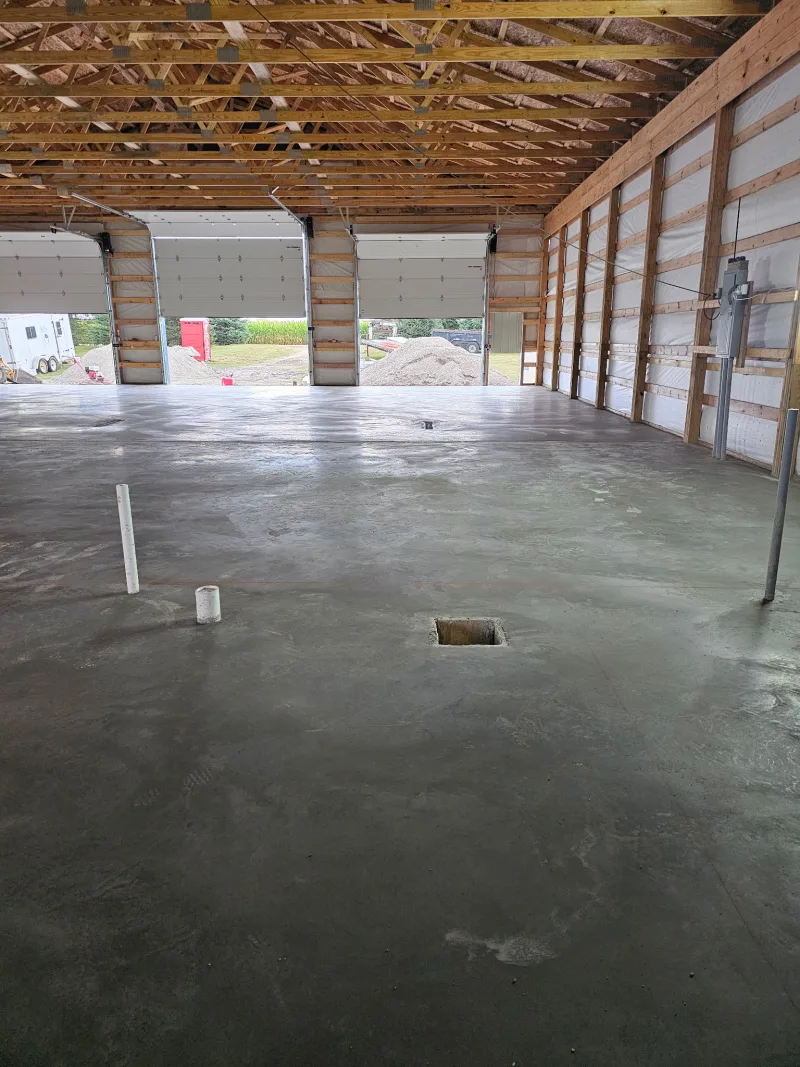 Interior of a finished pole barn with poured concrete floor and overhead doors