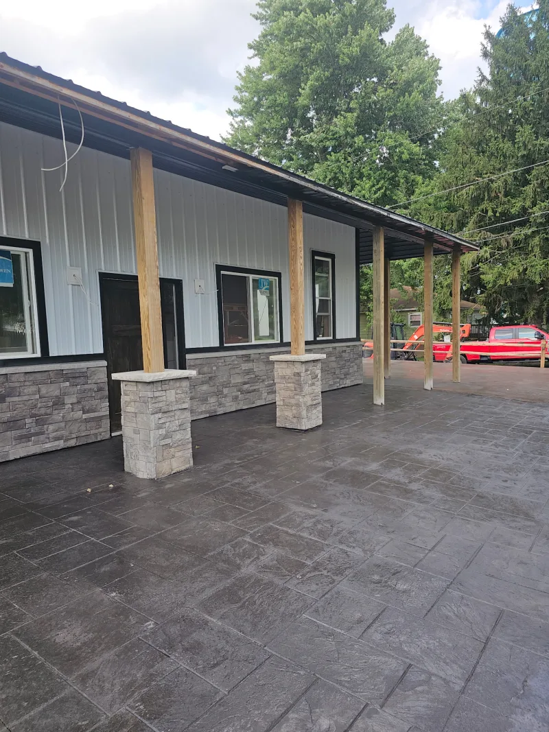 Barndominium porch with stacked-stone columns and stamped concrete floor