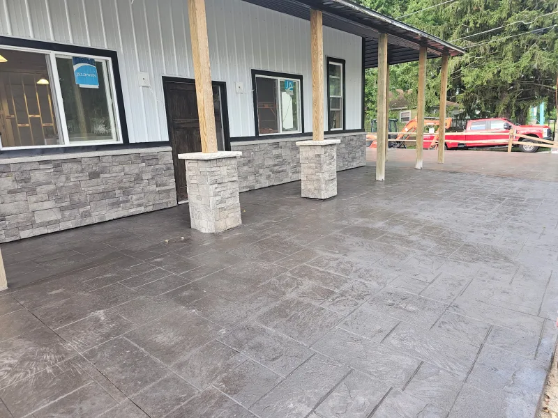 White barndominium with stone wainscot and stamped-concrete covered porch