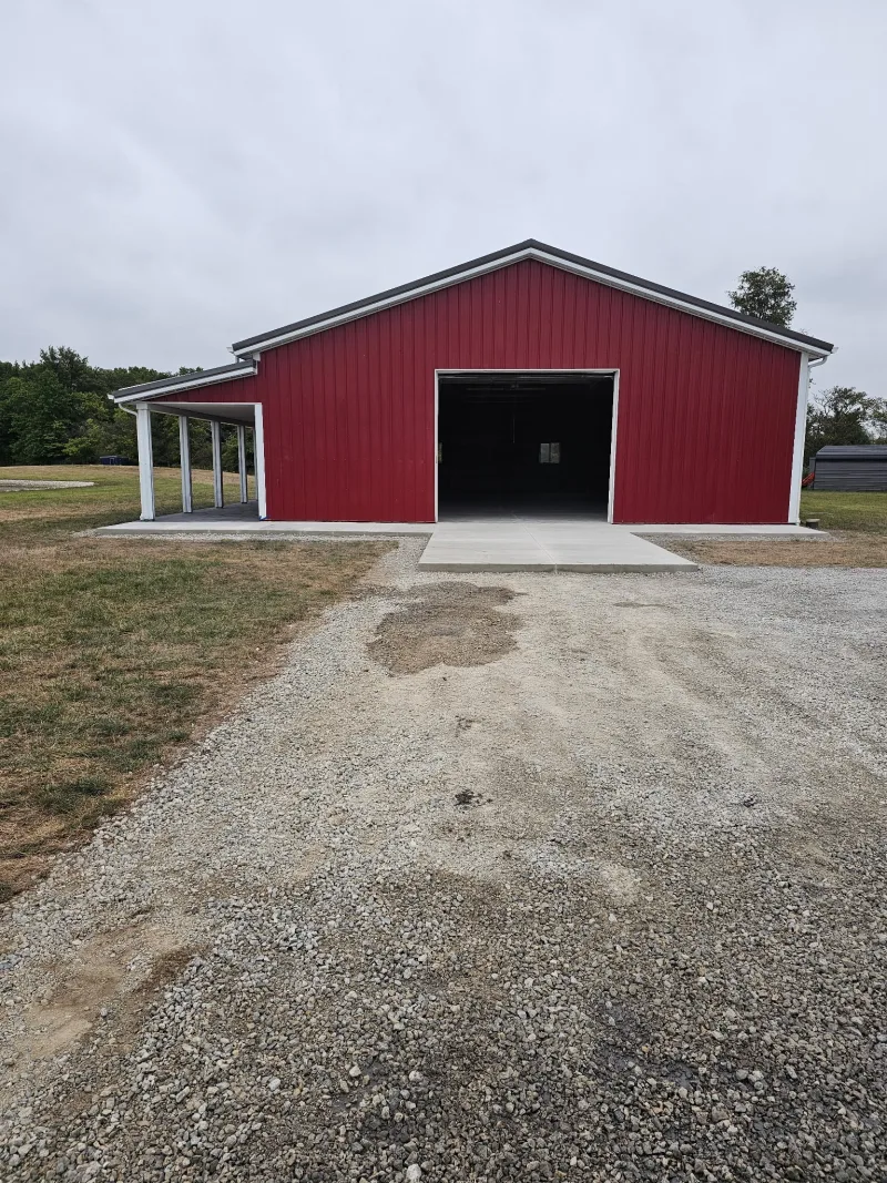 Completed red post-frame barn with gable end and lean-to